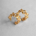 Nahaufnahme goldener Faltenblumen-Ohrringe mit 925er Silbernadeln auf grauem Sandhintergrund - Gold