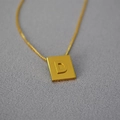 Dettaglio macro del ciondolo a lettera quadrata dorata D su una collana a catena semplice - Lettera D