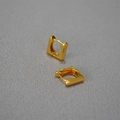 Nahaufnahme der geometrischen quadratischen Ohrringe aus vergoldetem Messing auf Grau - Gold