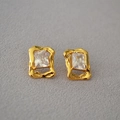 Vista macro di orecchini a perno in ottone dorato con dettaglio in zirconia rettangolare - Bianco
