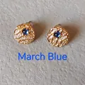 Detailed view of gold textured disc earrings with March Blue gemstones on stone - 1cm-March Blue