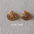 Detail of vintage gold stud earrings with June Opal stone and hammered texture surface - 1cm-June Opal