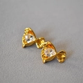 Detailansicht der goldfarbenen Zuckerblumen-Ohrstecker mit Zirkon auf grauem Stoff - Weiß