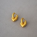 Minimalistische dick vergoldete Messing-Herzohrringe auf grauem strukturiertem Hintergrund - Goldfarbener 3D-Herz-Stil / Gold