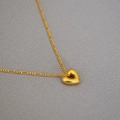 Dettaglio macro del ciondolo a cuore placcato oro 18K con catena Figaro su sfondo grigio - Cuore Oro Vintage