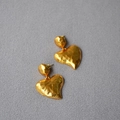 Detail von gehämmerten vergoldeten Herzohrringen mit 925 Silbersteckern auf Grau - Altgold