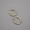Minimalistische silberne Creolen mit facettierten Metallperlen auf grauem Stoffhintergrund - Weißgold