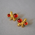 Dettaglio ravvicinato di orecchini vintage dorati con texture lavica e pietre rosse - Rosso