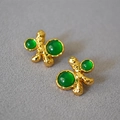 Dettaglio di orecchini vintage dorati con pietre preziose verdi su fondo in maglia - Verde