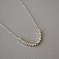 Minimalist silver O-chain necklace featuring small faceted cube metal beads on a grey base - Platinum Plated