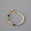 Detail of beaded necklace with freshwater pearls, tiger eye, and stones on a grey base - Horseshoe Woven Bracelet