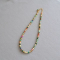 Detail of colorful beaded necklace with gold spacers and lobster clasp on grey fabric - Necklace