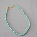 Detailed macro view of bohemian beaded necklace with turquoise stones and golden spacers - Turquoise