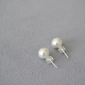 Dettaglio di grandi orecchini a perno con perle bianco opaco su tessuto grigio - 8mm / Stile Fiore di Cotone