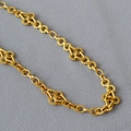 Dettaglio ravvicinato di anelli a ingranaggio e maglie geometriche su collana d'oro - Oro Anticato