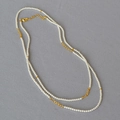 Elegante collana a due strati con perle bianche, dettagli dorati e chiusura a moschettone - Bianco