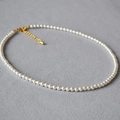 Detail einer eleganten Perlenkette mit goldenem Karabinerverschluss und Kette - 4mm Marke Künstliche Perle