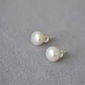 Detail of 925 silver stud earrings with white freshwater pearls on grey fabric - Approx. 9-10mm
