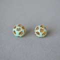 Dettaglio macro di orecchini a sfera traforati con smalto blu e motivi a cuore oro - Blu