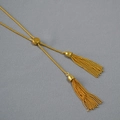 Dettaglio macro della perla scorrevole e doppie nappe su collana dorata vintage regolabile - Collana