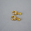 Minimalistische 18K Gold Creolen mit gelbem Zirkonia Anhänger auf grauem Stoffhintergrund - Gelb
