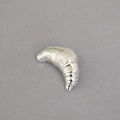 Broche de plata pulida en forma de cruasán con textura irregular sobre tela gris - Plateado