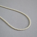 Dettaglio macro di perle artificiali bianco crema da 3-4mm con elegante finitura lucida - 4mm