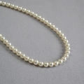 Collier élégant à un rang de perles crème sur fond texturé gris - 6mm