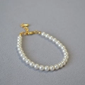 Primo piano di un elegante bracciale di perle bianche con chiusura e catena dorata - 5mm