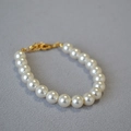 Vue détaillée d'un élégant bracelet de perles blanches avec fermoir mousqueton doré - 8mm