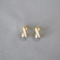 Vue détaillée des boucles d'oreilles en émail avec bordure dorée et design croisé - Blanc