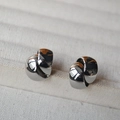 Makroaufnahme polierter silberner Knoten-Ohrstecker in einer minimalistischen Schmuckschachtel - Silber