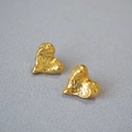Detailed close-up of vintage heart earrings with gold lava texture on grey fabric - Antique Gold