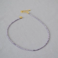 Detalle macro de collar de cuentas de amatista púrpura con cadena dorada ajustable - Violeta