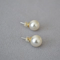Minimalist 925 silver needle pearl stud earrings with clear silicone backs on grey fabric - Color Code 650 (12mm)