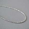 Dettaglio macro della collana di perline d'argento sfaccettate con lucentezza metallica fine - Perline Piatte Romboidali Argentate