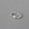 Minimalistische zilveren getextureerde ring met ronde parel op grijze stoffen achtergrond - Ruit Witte Parel