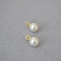 Classic round white pearl stud earrings with golden 925 silver posts on grey fabric - Color Code 650 (10mm)