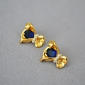 Detail van goudkleurige oorbellen in snoepvorm met blauwe edelsteen en kleine witte parels - Blauw