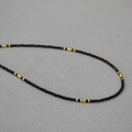 Detailed macro view of French style faceted black spinel necklace with gold beads - Black+Gold