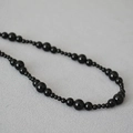 Dettaglio macro dell'elegante collana di onice nera con gemme lucide di varie dimensioni - Agata nera