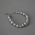 Detail of silver grey pearl bracelet with graduated sizes and silver lobster clasp on fabric - Silver Grey Bracelet