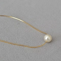 Primer plano de un collar de oro con un elegante colgante de perla blanca única - Blanco Crema (10mm)
