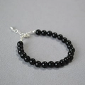 Detailed shot of beaded bracelet with black onyx stones and silver adjustable metal clasp - 6mm / Black Agate