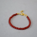 Detailed shot of red agate beaded bracelet with gold lobster clasp on grey fabric - 4mm / Red Agate
