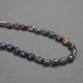 Collar de perlas barrocas de Tahití verde pavo real con brillo irisado sobre tela gris - Estilo 1