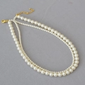 Dettaglio di elegante collana di perle a due strati con perle lucide e chiusura dorata - Bianco Sporco