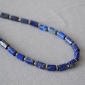 Dettaglio macro di perline cilindriche di lapislazzuli con distanziatori dorati su collana - Lapislazzuli