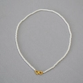 Detail of elegant pearl necklace featuring a golden infinity clasp over grey fabric - Creamy White Necklace 3mm