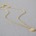Primo piano dettagliato di una collana dorata con ciondolo a forma di smile in madreperla - 1 Collana